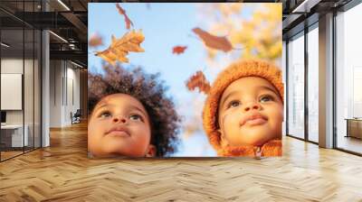 two african american toddlers wearing modern warm autumn clothes with autumn leaves levitating pattern, colorful autumn forest in the background Wall mural