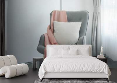 Pink scarf and beige pillow on gray armchair at the corner of living room Wall mural