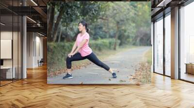 Asian girl is stretching her body warm muscles before going out for a run at the park Wall mural