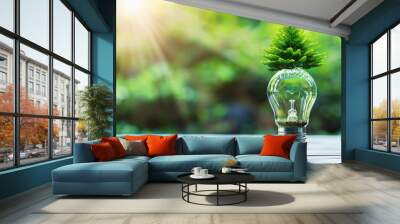 Green energy concept with a light bulb and tree inside on a wooden table against a green nature background, copy space for an eco friendly environment and sustainable development Wall mural