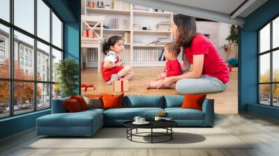 A mother and her two children are playing together in the living room, which is decorated for the upcoming Christmas celebration Wall mural