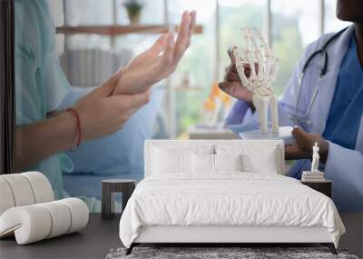 Doctor showing model of finger bones to patient in hospital. Medical and healthcare concept. Wall mural