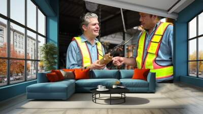 Two workers on a construction site are demonstrating the operation of a crane controller in an industrial plant Wall mural