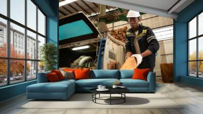 Young man worker work in a woodworking factory, Working with wood sawing and cutting machines to produce wooden sheets for making pallets Wall mural