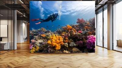 Diver exploring vibrant coral reef teeming with colorful marine life in tropical waters on a sunny day Wall mural