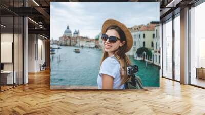 Happy smiling tourist girl posing on a bridge in front of Grand Canal and Basilica Santa Maria della Salute in Venice Wall mural