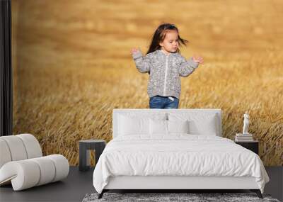 Happy 2 year old girl walking in a summer harvested field Wall mural