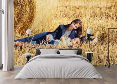 Happy mother and 2 year old girl next to hay bales in harvested field Wall mural