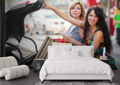 young women loading shopping bags in a car trunk Wall mural