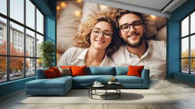 Happy western couple in glasses lying on the bed Wall mural