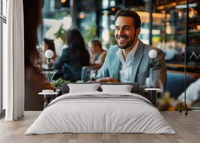 Business Lunch Laughter: A handsome businessman enjoys a lively conversation and delicious food at a bustling restaurant. Wall mural