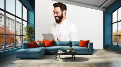 Smiling businessman working on laptop and tablet in office Wall mural