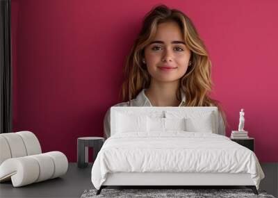 Young professional woman with a cheerful expression, posed against a vivid pink background Wall mural