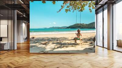 Beautiful girl swinging on wooden swing on the tree at the beach, happy smiling girl with red hair, playing on the beach on vacation trip, at Parnaioca beach, in Ilha Grande, in Rio de Janeiro, Brazil Wall mural