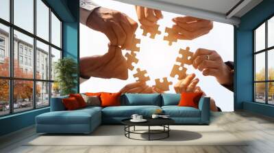 The hand of a businessman holding a paper jigsaw And solving the puzzle together. The business team assembles a jigsaw puzzle. A business group wishing to bring together the puzzle pieces Wall mural