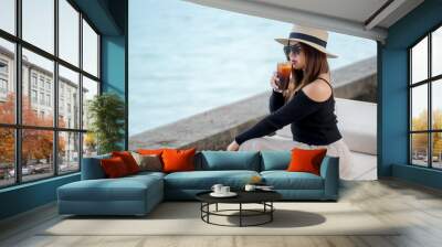 Young woman sitting alone watching the sea in Phuket, relaxing on vacation. Wall mural