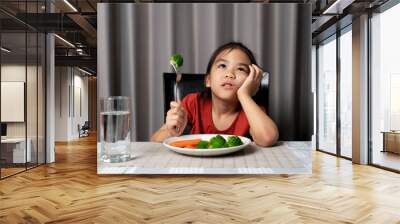 Little cute kid girl refusing to eat healthy vegetables. Children do not like to eat vegetables. Wall mural