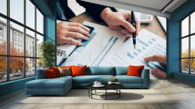 The accounting staff of the company are jointly analyzing the graph of the expenses on the desk in the office. Wall mural