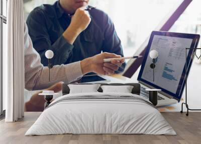 Two businessmen are together analyzing the financial data graph and pointing to the laptop computer screen. Wall mural