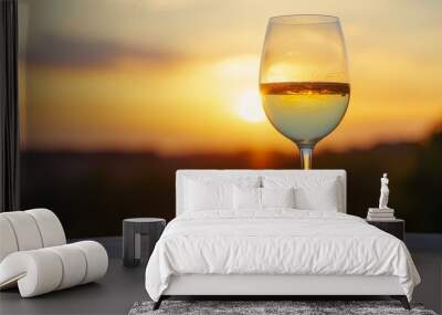 glass of white wine on a table as the sun sets in the background on a warm summer night Wall mural