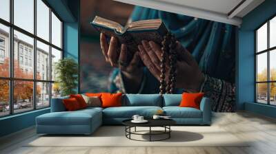 Person holding a Quran and prayer beads, deeply engrossed in worship, with a serene and spiritual atmosphere. Wall mural