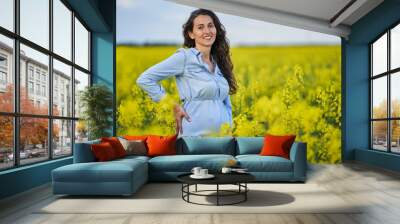 Pregnant woman in a canola field Wall mural