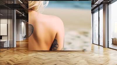 A blonde woman on vacation on the beach features a heart tattoo on her bare back, inviting love and inspiration. Generative AI Wall mural