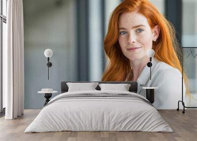 Portrait of a confident redhead woman with freckles, wearing professional attire and holding a digital tablet, symbolizing empowerment in the workplace. Wall mural