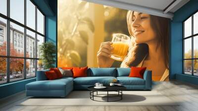 Sunny woman sipping orange juice in a morning garden. Wall mural