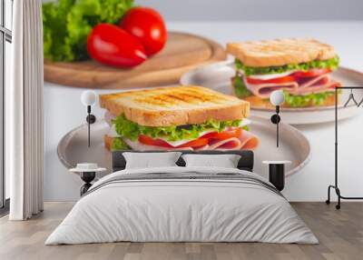 Close-up of two sandwiches with bacon, salami, prosciutto and fresh vegetables on rustic wooden cutting board. Club sandwich concept Wall mural