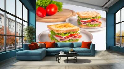 Close-up of two sandwiches with bacon, salami, prosciutto and fresh vegetables on rustic wooden cutting board. Club sandwich concept Wall mural