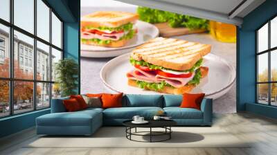 Close-up of two sandwiches with bacon, salami, prosciutto and fresh vegetables on rustic wooden cutting board. Club sandwich concept Wall mural