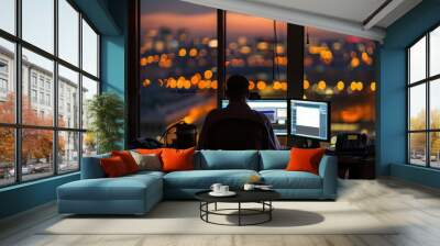 A man is sitting at a desk with two computer monitors in front of him Wall mural