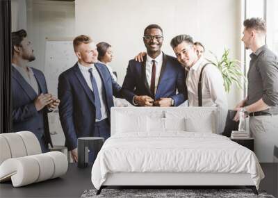 A team of young businessmen working and communicating together in an office. Corporate businessteam and manager in a meeting. handshake Wall mural