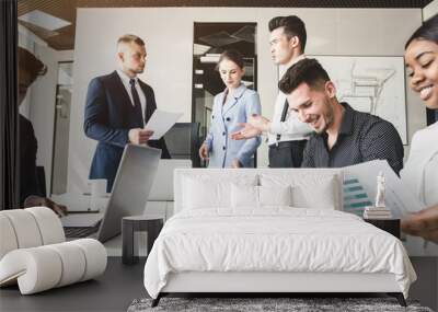 A team of young businessmen working and communicating together in an office. Corporate businessteam and manager in a meeting. Wall mural