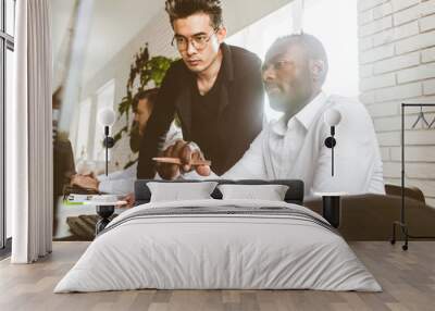 A team of young businessmen working and communicating together in an office. Corporate businessteam and manager in a meeting. Wall mural