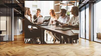 A team of young businessmen working and communicating together in an office. Corporate businessteam and manager in a meeting. Wall mural