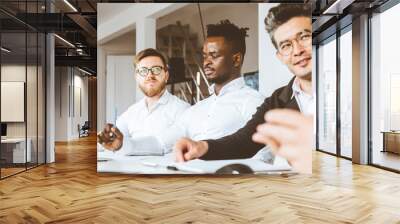 A team of young businessmen working and communicating together in an office. Corporate businessteam and manager in a meeting. Wall mural