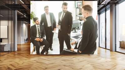 A team of young businessmen working and communicating together in an office. Corporate businessteam and manager in a meeting. Wall mural