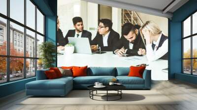 A team of young businessmen working and communicating together in an office. Corporate businessteam and manager in a meeting. Wall mural