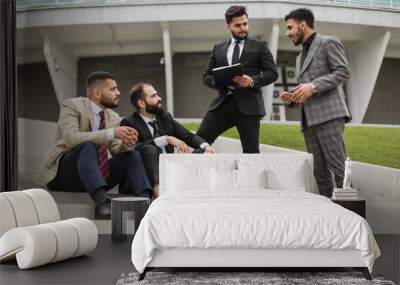 Business people outdoor meeting. A company of male businessmen in suits are sitting on the steps of the stairs. Working break. Teamwork and brainstorming. Successful teamwork Wall mural