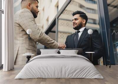 Business people outdoor meeting. Two men in suits hold out their hands to each other. A handshake is a mutual agreement. Greeting and interpersonal contact Wall mural