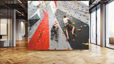 couple of athletes climber moving up on steep rock, climbing on artificial wall indoors. Extreme sports and bouldering concept Wall mural