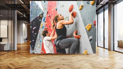 couple of athletes climber moving up on steep rock, climbing on artificial wall indoors. Extreme sports and bouldering concept Wall mural