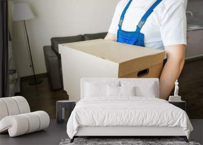 Delivery man loading cardboard boxes for moving to an apartment. professional worker of transportation, male loaders in overalls Wall mural