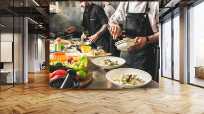 Professional chef cooking in the kitchen restaurant at the hotel, preparing dinner. A cook in an apron makes a salad of vegetables and pizza. Wall mural