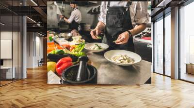 Professional chef cooking in the kitchen restaurant at the hotel, preparing dinner. A cook in an apron makes a salad of vegetables and pizza. Wall mural