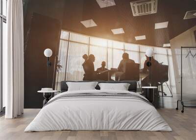 Silhouettes of people sitting at the table. A team of young businessmen working and communicating together in an office. Corporate businessteam and manager in a meeting Wall mural