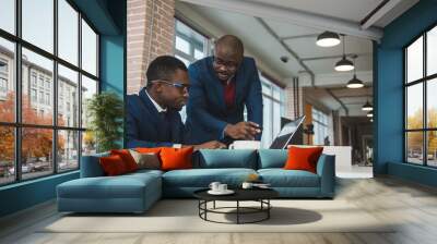 Two dark-skinned partners of an African American businessman in a meeting work on a laptop in the office. Affordable private courses and distance learning. New opportunities online Wall mural