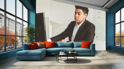 Young office worker sitting at desk, using computer. Two business man talking Wall mural